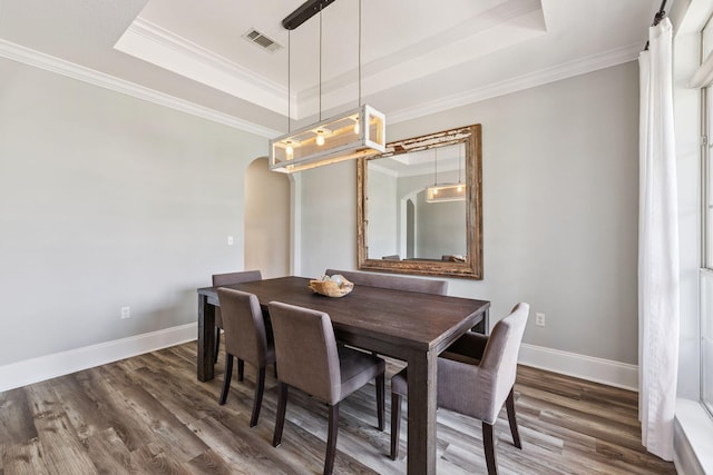 134 Mussett Bayou Ct, Santa Rosa Beach, FL 32459 - dining room featuring a tray ceiling, arched walkways, wood finished floors, and ornamental molding
