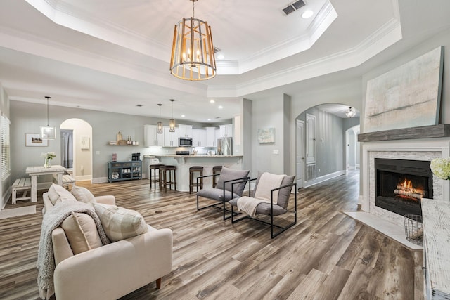 134 Mussett Bayou Ct, Santa Rosa Beach, FL 32459 - living room with arched walkways, wood finished floors, a tray ceiling, a chandelier, and crown molding