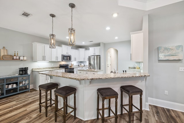 134 Mussett Bayou Ct, Santa Rosa Beach, FL 32459 - kitchen featuring appliances with stainless steel finishes, a peninsula, dark wood-style floors, light stone counters, and white cabinetry