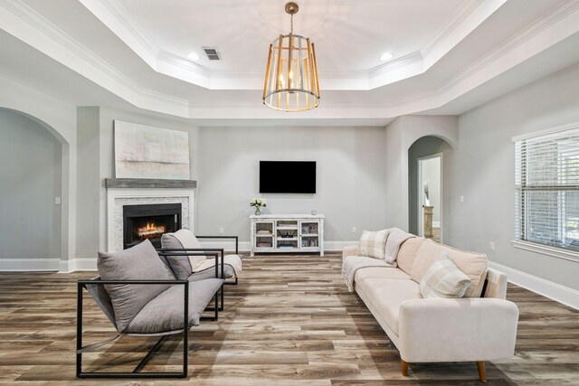 134 Mussett Bayou Ct, Santa Rosa Beach, FL 32459 - living area with arched walkways, a raised ceiling, wood finished floors, a warm lit fireplace, and crown molding