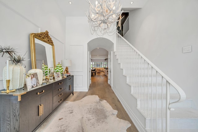 34 E Surfside Dr, Santa Rosa Beach, FL 32459 - stairs with arched walkways, a chandelier, wood finished floors, and a towering ceiling