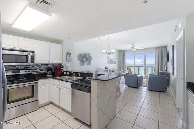15817 Front Beach Rd # 706, Panama City Beach, FL 32413 - kitchen featuring stainless steel appliances, a peninsula, light tile patterned floors, dark countertops, and backsplash