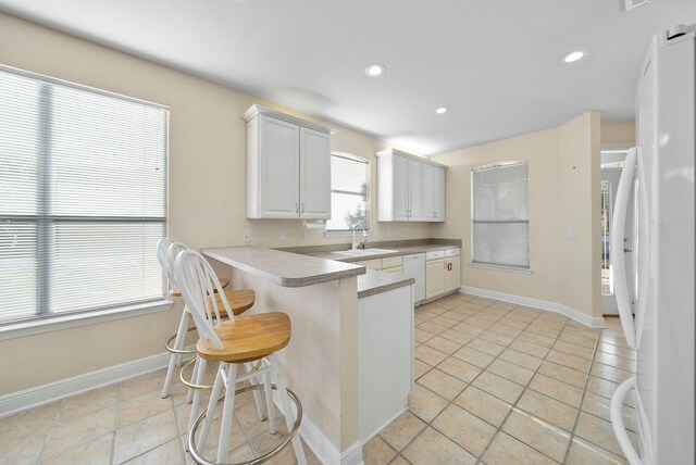 94 Terra Cotta Way, Destin, FL 32541 - kitchen featuring white appliances, a breakfast bar area, light countertops, white cabinetry, and recessed lighting