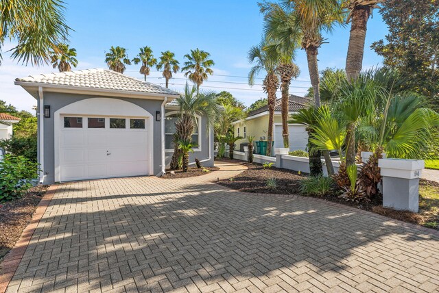 94 Terra Cotta Way, Destin, FL 32541 - mediterranean / spanish house featuring an attached garage, decorative driveway, stucco siding, and a tiled roof