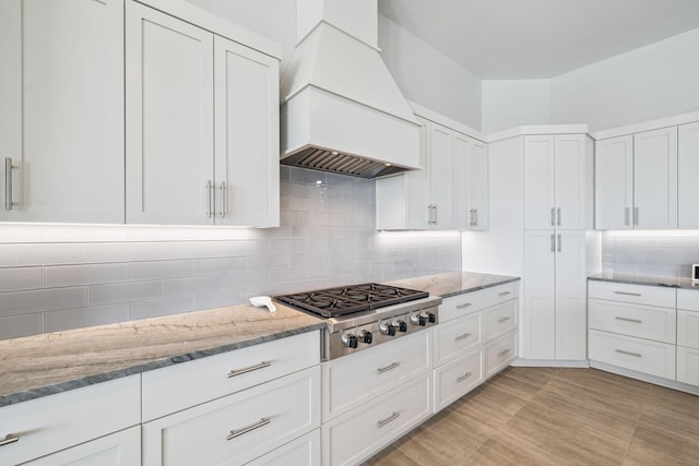 31 Driftwood Ct, Santa Rosa Beach, FL 32459 - kitchen featuring stainless steel gas stovetop, custom range hood, white cabinetry, light stone counters, and backsplash