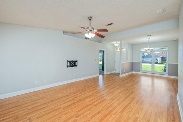 8562 Vehlin Ct, Navarre, FL 32566 - unfurnished living room featuring light wood-style floors, plenty of natural light, a chandelier, ceiling fan, and a textured ceiling