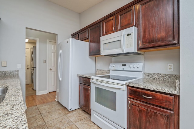 8562 Vehlin Ct, Navarre, FL 32566 - kitchen featuring white appliances, stacked washer / drying machine, light tile patterned floors, and light stone counters