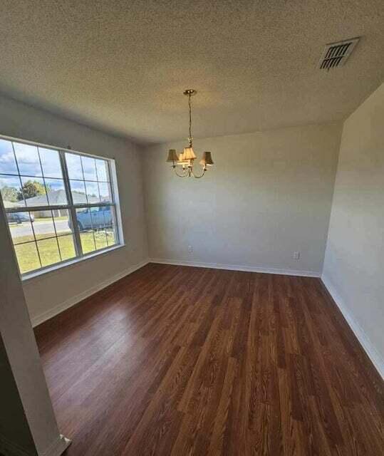 294 Limestone Cir, Crestview, FL 32539 - unfurnished dining area featuring dark wood finished floors, a chandelier, and a textured ceiling
