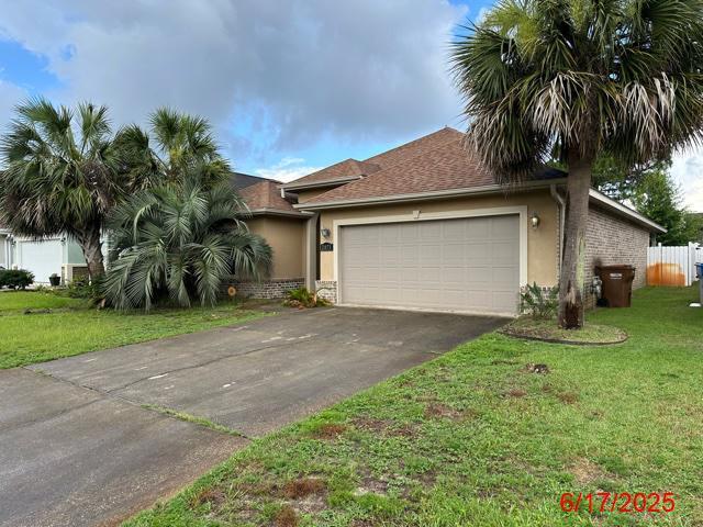 2071 Fountainview Dr, Navarre, FL 32566 - view of front of house featuring stucco siding, driveway, a garage, and a front yard
