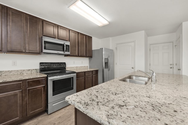 718 Widgeon Way, Crestview, FL 32539 - kitchen featuring stainless steel appliances, light wood finished floors, dark brown cabinets, and light stone counters