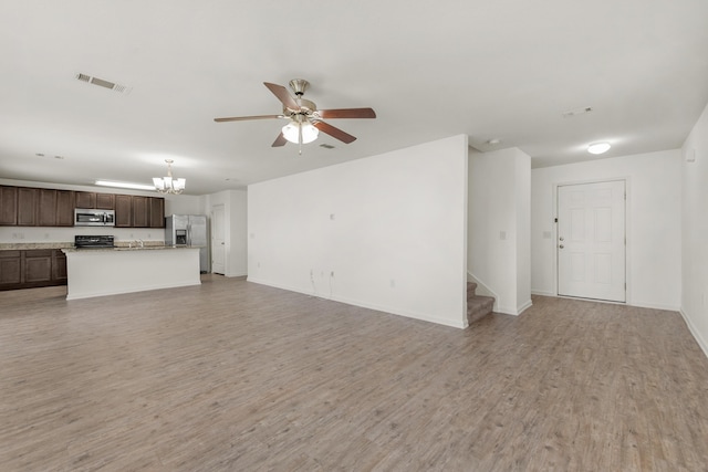 718 Widgeon Way, Crestview, FL 32539 - unfurnished living room featuring a ceiling fan, a chandelier, stairs, and light wood-type flooring
