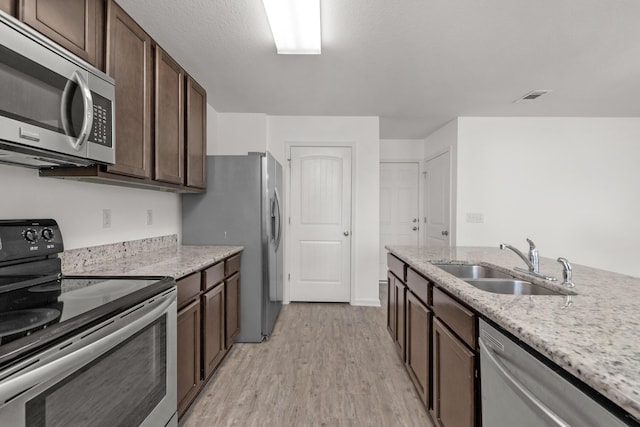 718 Widgeon Way, Crestview, FL 32539 - kitchen with stainless steel appliances, light wood-style floors, dark brown cabinets, and light stone countertops