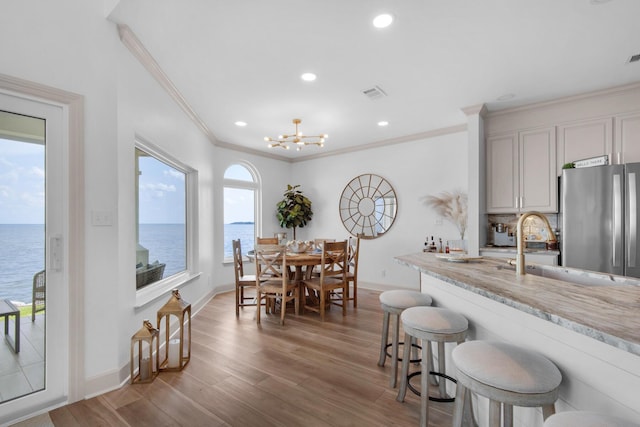 961 Northshore Dr, Miramar Beach, FL 32550 - kitchen with freestanding refrigerator, crown molding, wood finished floors, a kitchen breakfast bar, and a water view