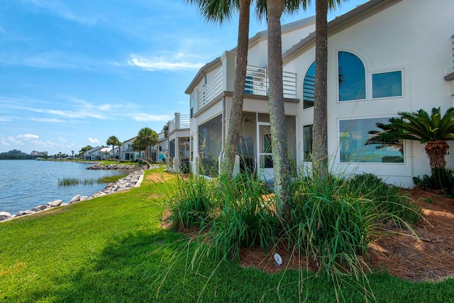 961 Northshore Dr, Miramar Beach, FL 32550 - view of side of property with stucco siding, a water view, a lawn, and a sunroom