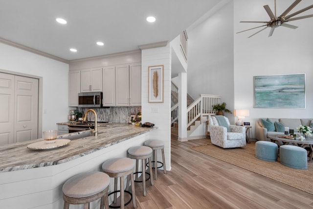 961 Northshore Dr, Miramar Beach, FL 32550 - kitchen featuring appliances with stainless steel finishes, a kitchen bar, backsplash, ceiling fan, and light wood-style flooring