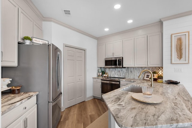 961 Northshore Dr, Miramar Beach, FL 32550 - kitchen featuring appliances with stainless steel finishes, a peninsula, light wood finished floors, light stone countertops, and tasteful backsplash