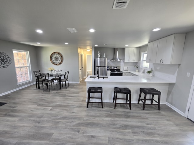 726 Clark Dr, Fort Walton Beach, FL 32547 - kitchen featuring appliances with stainless steel finishes, wall chimney range hood, a peninsula, recessed lighting, and white cabinets