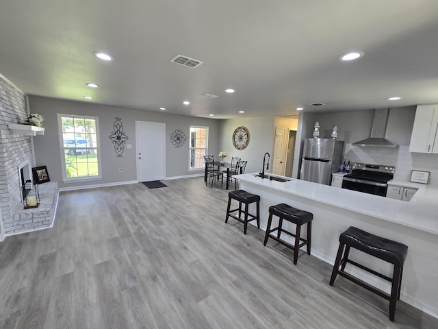 726 Clark Dr, Fort Walton Beach, FL 32547 - kitchen with wall chimney exhaust hood, stainless steel appliances, a breakfast bar area, recessed lighting, and light countertops