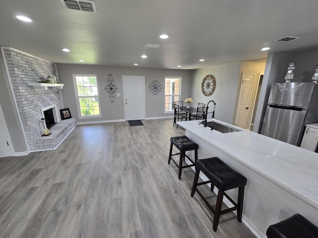 726 Clark Dr, Fort Walton Beach, FL 32547 - kitchen featuring freestanding refrigerator, a kitchen breakfast bar, light wood-style floors, recessed lighting, and light stone counters