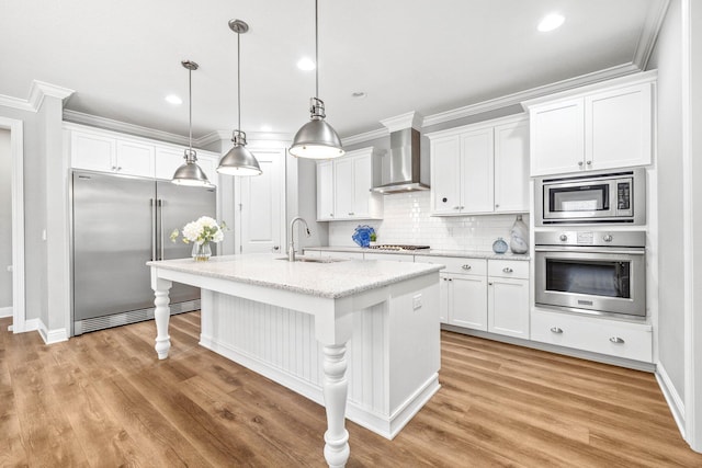 129 Meadow Lake Dr, Freeport, FL 32439 - kitchen featuring built in appliances, wall chimney range hood, white cabinets, light wood-style flooring, and ornamental molding