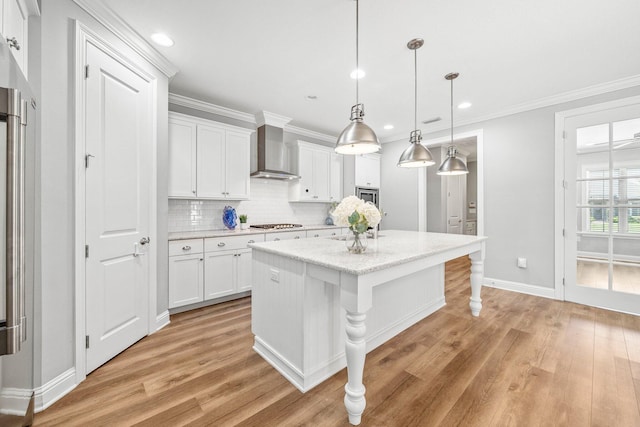 129 Meadow Lake Dr, Freeport, FL 32439 - kitchen featuring wall chimney range hood, white cabinets, light wood-type flooring, tasteful backsplash, and a center island