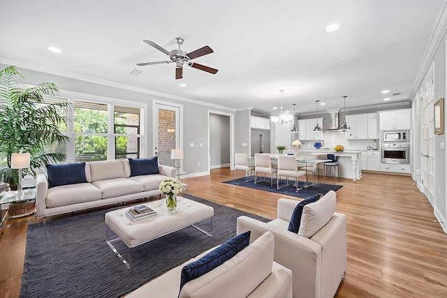 129 Meadow Lake Dr, Freeport, FL 32439 - living room with crown molding, a ceiling fan, light wood-style floors, recessed lighting, and a chandelier