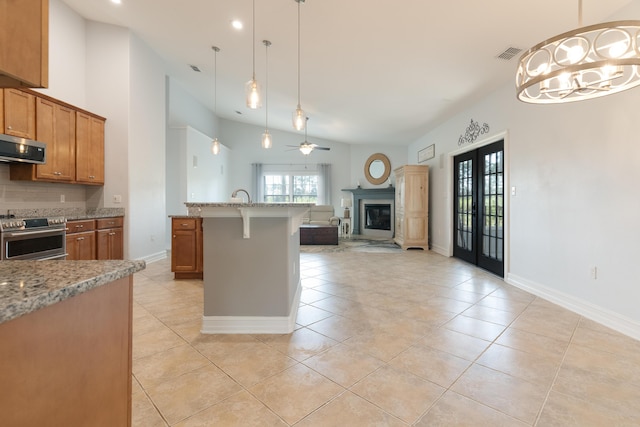 180 Gulf Pines Ct, Freeport, FL 32439 - kitchen featuring stainless steel range, open floor plan, a glass covered fireplace, brown cabinets, and a kitchen bar