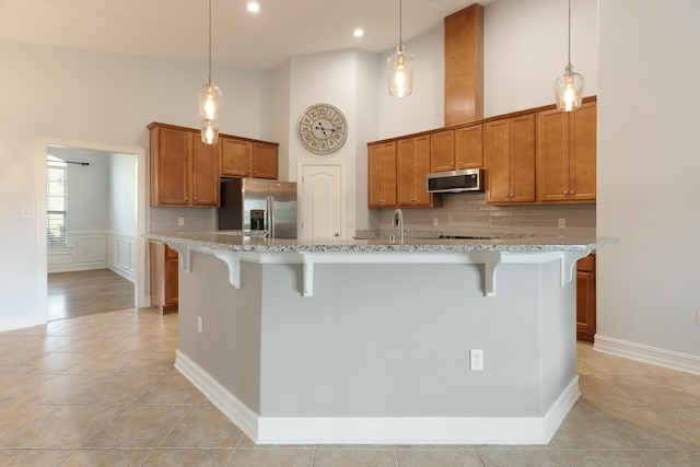 180 Gulf Pines Ct, Freeport, FL 32439 - kitchen featuring stainless steel appliances, a breakfast bar, decorative backsplash, brown cabinetry, and light stone countertops