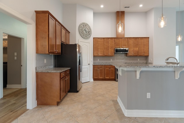 180 Gulf Pines Ct, Freeport, FL 32439 - kitchen featuring stainless steel appliances, brown cabinets, a breakfast bar area, a high ceiling, and recessed lighting