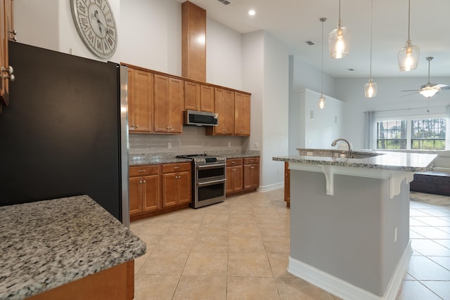 180 Gulf Pines Ct, Freeport, FL 32439 - kitchen featuring appliances with stainless steel finishes, brown cabinets, tasteful backsplash, a breakfast bar area, and recessed lighting