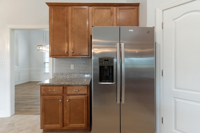 180 Gulf Pines Ct, Freeport, FL 32439 - kitchen featuring stainless steel refrigerator with ice dispenser, brown cabinetry, stone countertops, and light tile patterned flooring