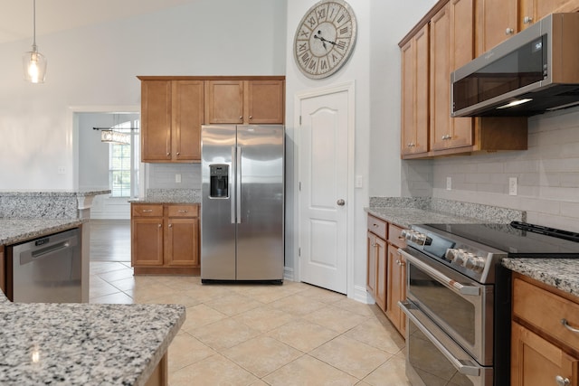 180 Gulf Pines Ct, Freeport, FL 32439 - kitchen with stainless steel appliances, tasteful backsplash, light tile patterned floors, brown cabinetry, and light stone counters
