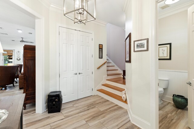 2077 Olde Towne Ave, Miramar Beach, FL 32550 - foyer entrance with ornamental molding, stairs, a wainscoted wall, a chandelier, and light wood finished floors
