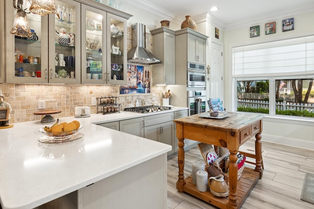 2077 Olde Towne Ave, Miramar Beach, FL 32550 - kitchen with wall chimney exhaust hood, gray cabinets, ornamental molding, light countertops, and tasteful backsplash