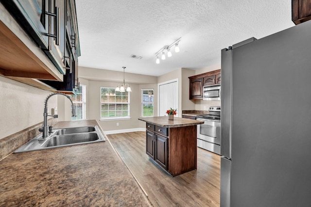 653 Territory Ln, Crestview, FL 32536 - kitchen featuring appliances with stainless steel finishes, light wood-style floors, a center island, dark brown cabinets, and decorative light fixtures