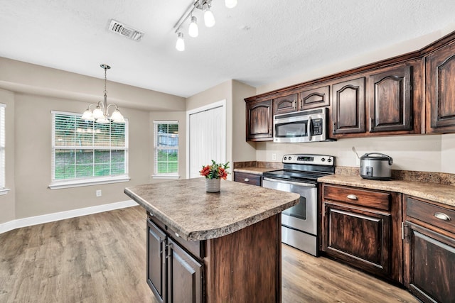 653 Territory Ln, Crestview, FL 32536 - kitchen featuring stainless steel appliances, light wood-style flooring, a center island, healthy amount of natural light, and a textured ceiling