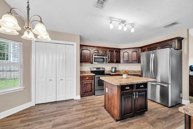 653 Territory Ln, Crestview, FL 32536 - kitchen featuring appliances with stainless steel finishes, a chandelier, light countertops, dark brown cabinetry, and a center island