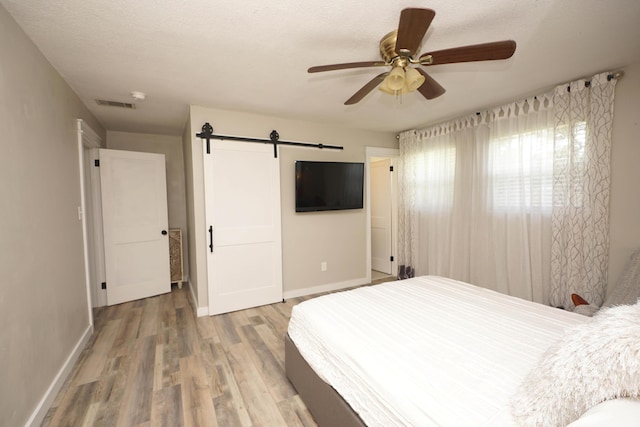 52 NE Iowa Dr, Fort Walton Beach, FL 32548 - bedroom with a barn door, wood finished floors, and ceiling fan