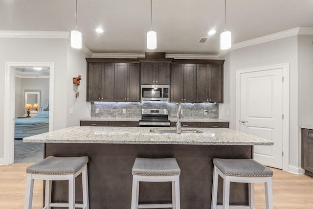 1922 Frontera St, Navarre, FL 32566 - kitchen featuring stainless steel appliances, crown molding, a breakfast bar area, and dark brown cabinets