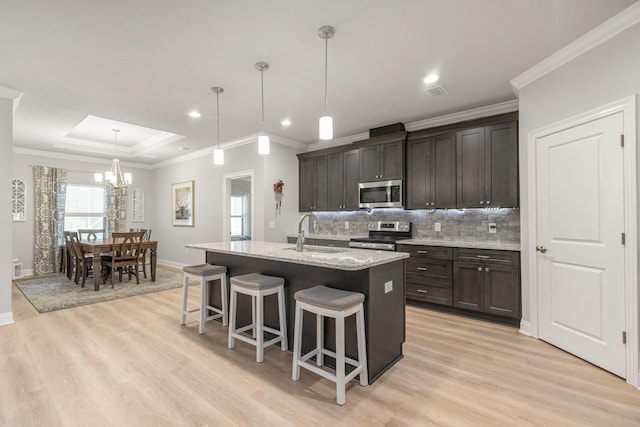 1922 Frontera St, Navarre, FL 32566 - kitchen featuring stainless steel appliances, light wood finished floors, a breakfast bar, a chandelier, and ornamental molding