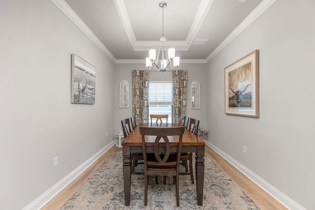 1922 Frontera St, Navarre, FL 32566 - dining space featuring light wood-style flooring, a chandelier, a tray ceiling, and crown molding