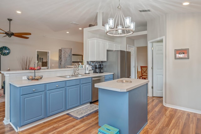 337 Peggy Dr, Crestview, FL 32536 - kitchen with appliances with stainless steel finishes, blue cabinets, a peninsula, light wood-style floors, and white cabinetry