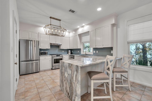 69 Lake Pointe Dr, Santa Rosa Beach, FL 32459 - kitchen with appliances with stainless steel finishes, a peninsula, light stone counters, white cabinetry, and recessed lighting