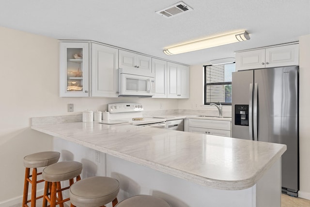 3705 E Old Highway 98 # 6, Destin, FL 32541 - kitchen with white appliances, a peninsula, white cabinetry, glass insert cabinets, and a breakfast bar