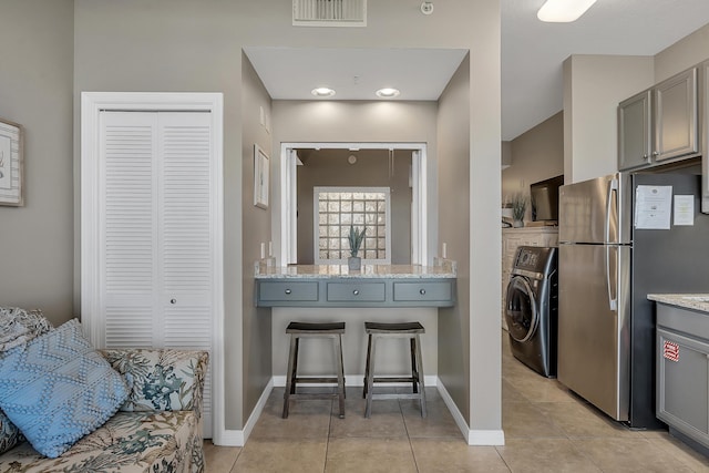1517 SW Miracle Strip Pkwy Unit 309, Fort Walton Beach, FL 32548 - kitchen with washer / clothes dryer, freestanding refrigerator, gray cabinetry, and light tile patterned floors