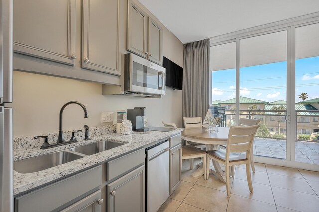 1517 SW Miracle Strip Pkwy Unit 309, Fort Walton Beach, FL 32548 - kitchen with appliances with stainless steel finishes, gray cabinets, light tile patterned floors, and light stone counters