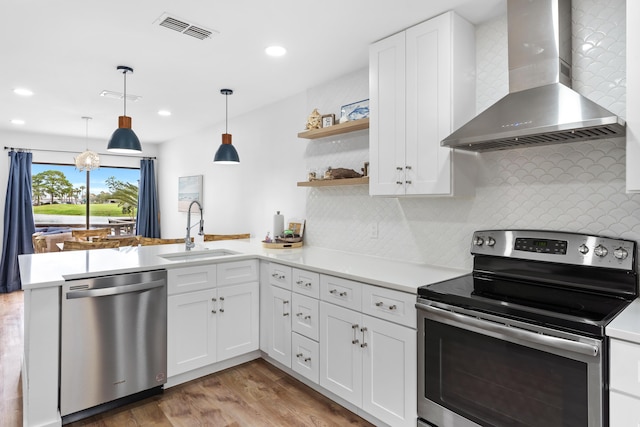 431 Linkside Cir, Miramar Beach, FL 32550 - kitchen featuring stainless steel appliances, wall chimney range hood, light countertops, a peninsula, and white cabinetry