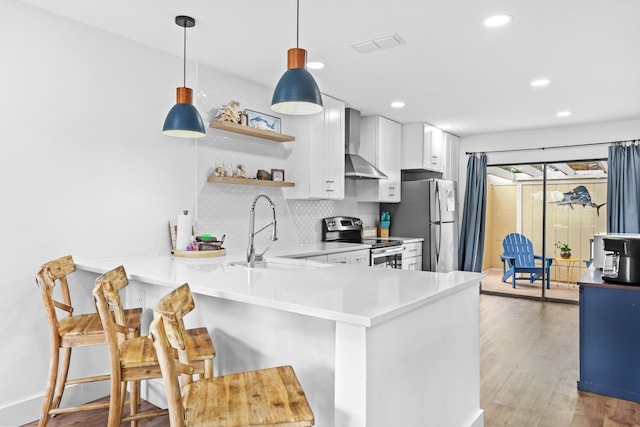 431 Linkside Cir, Miramar Beach, FL 32550 - kitchen featuring appliances with stainless steel finishes, wall chimney range hood, a breakfast bar area, tasteful backsplash, and a peninsula