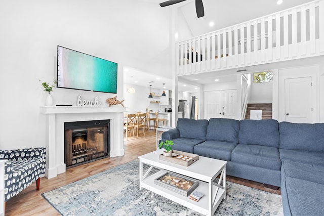431 Linkside Cir, Miramar Beach, FL 32550 - living room featuring stairway, a ceiling fan, wood finished floors, a high ceiling, and a fireplace
