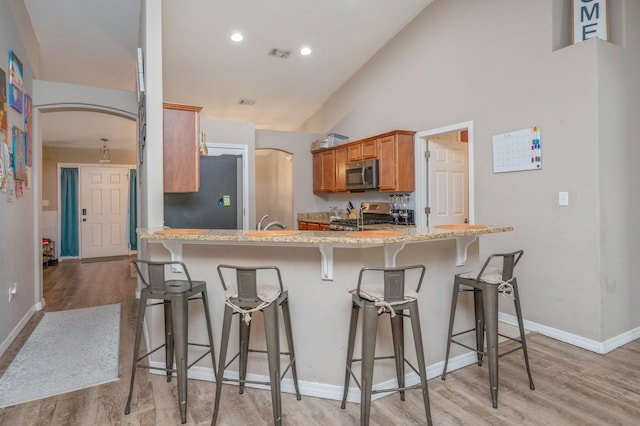 80 Azalea Trce, Defuniak Springs, FL 32433 - kitchen with stainless steel appliances, light wood finished floors, a breakfast bar, arched walkways, and recessed lighting